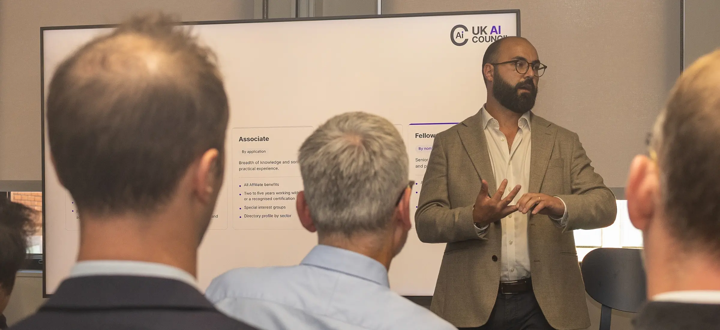 A UK AI Council speaker presenting membership tiers to colleagues at an event